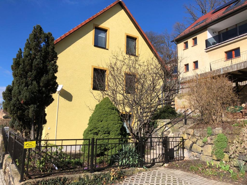 una casa amarilla con una valla delante en FeWo Kästner Pirna, en Pirna