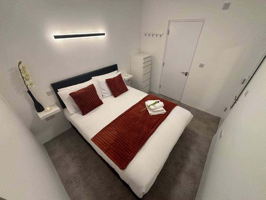 ein kleines weißes Schlafzimmer mit einem Bett mit roten Kissen in der Unterkunft Coastal Escape in Burtonport