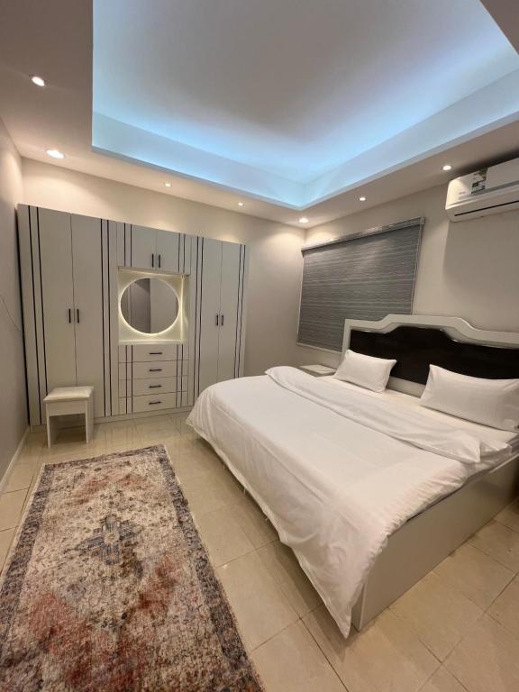 a bedroom with a large white bed and a rug at شقة مخدومه مفروشة قباء 303 in Al Madinah