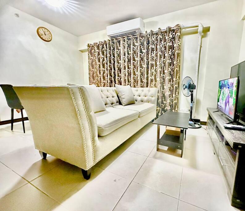 uma sala de estar com um sofá branco e um piano em 3BR Resort Style Condo em Manilla