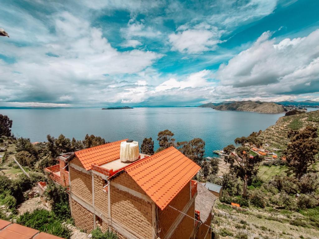 a house with an orange roof next to a body of water at Hostal Isla del Sol in Comunidad Yumani