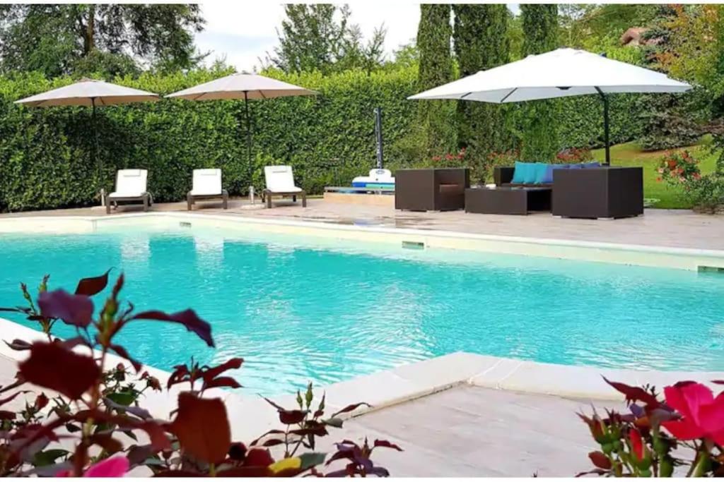 - une piscine avec 2 chaises longues et des parasols dans l'établissement Villa Bano Piemonte Private Pool, à Melazzo