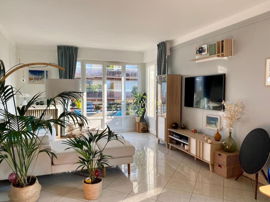un salon avec des plantes en pot et une télévision dans l'établissement Superbe appartement lumineux, à Neuilly-sur-Seine