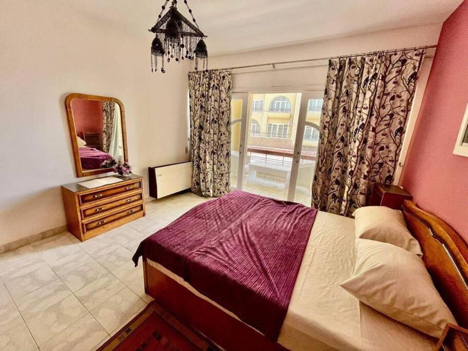 um quarto com uma cama, um espelho e uma janela em Palma de Meritee villa 2 apartment 4 village veiw em Hurghada