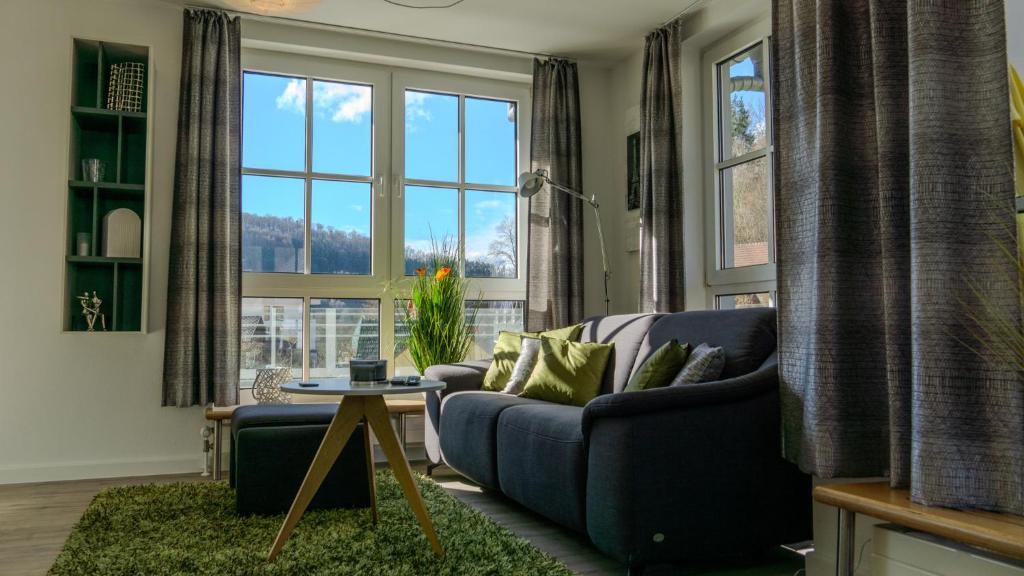 Großzügiges helles Penthouse mit Balkon in ruhiger Lage في كولمباخ: غرفة معيشة مع أريكة زرقاء ونوافذ كبيرة