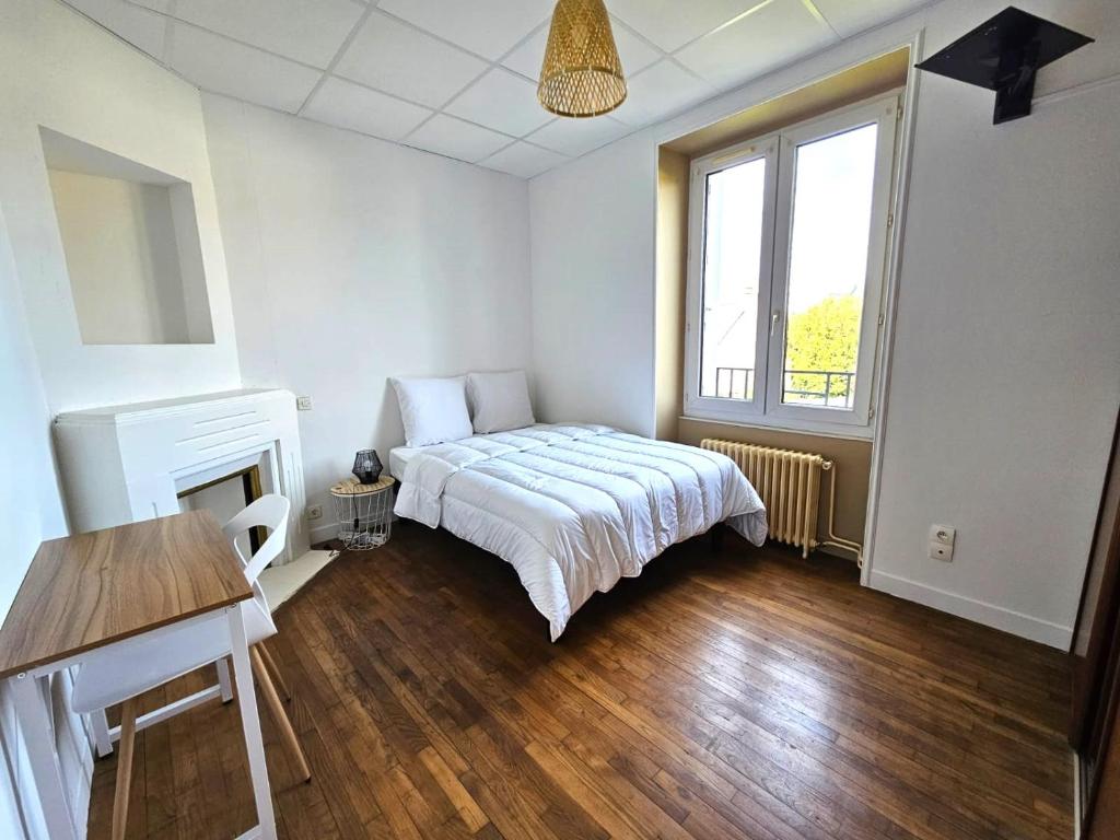 een slaapkamer met een bed, een tafel en een raam bij Chambre lumineuse en coloc in Ploërmel