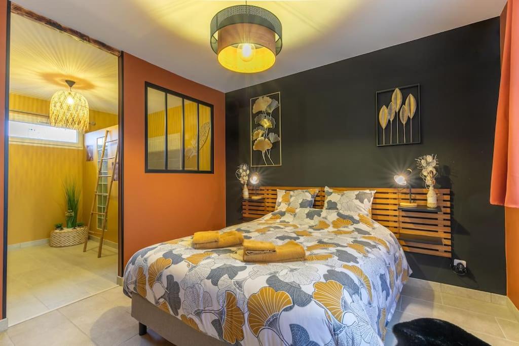 a bedroom with a large bed with orange walls at Au Doux Refuge - Maison - Parking gratuit in Romorantin