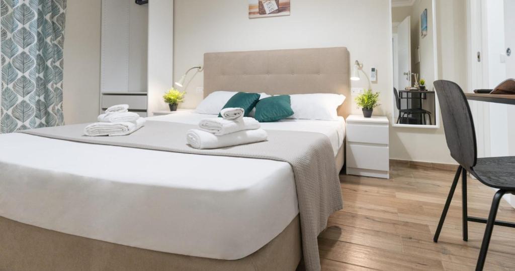 1 dormitorio con 1 cama blanca grande y toallas. en NeryHome Giardini Naxos, en Giardini Naxos