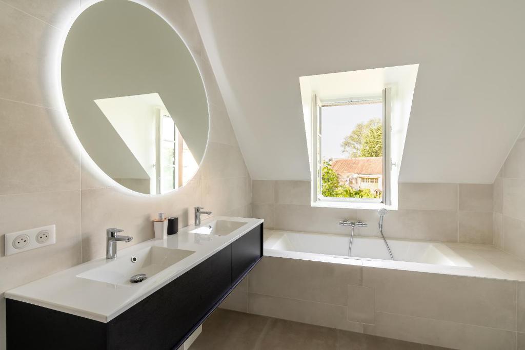 une salle de bain avec un lavabo, une baignoire et un miroir dans l'établissement Maison Oseraie, à Beynes
