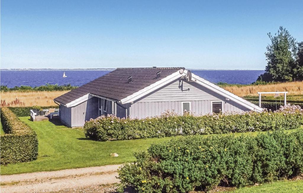 a barn with the ocean in the background at Holiday Home Bellevue Iii in Skovby