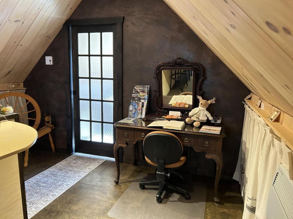 an attic room with a desk and a mirror at Appartement champêtre in Saguenay