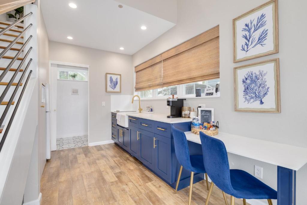 a kitchen with blue cabinets and blue chairs at SANDY - Cheerful 1 bedroom tiny house with pool in Dunedin