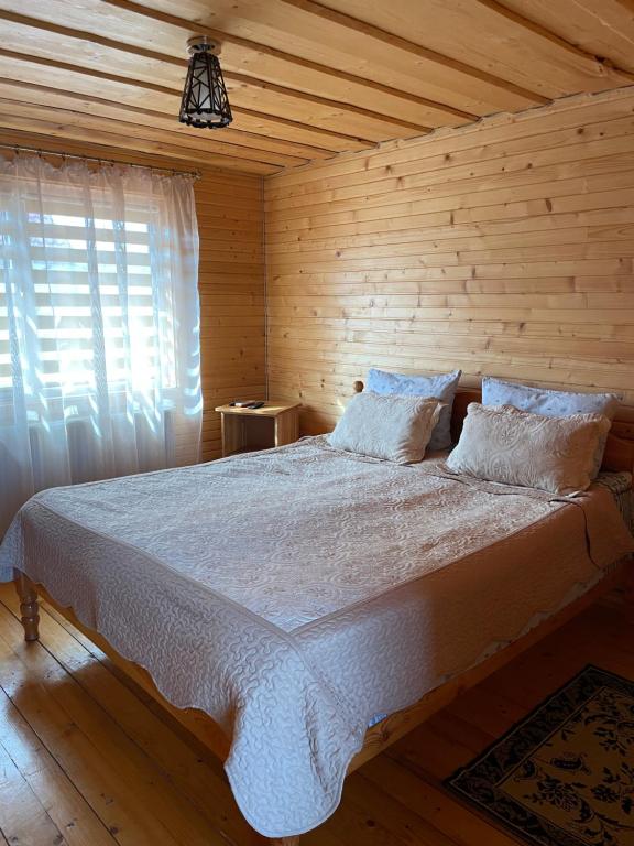 - une chambre avec un lit et un mur en bois dans l'établissement Azaliya, à Lazeshchyna