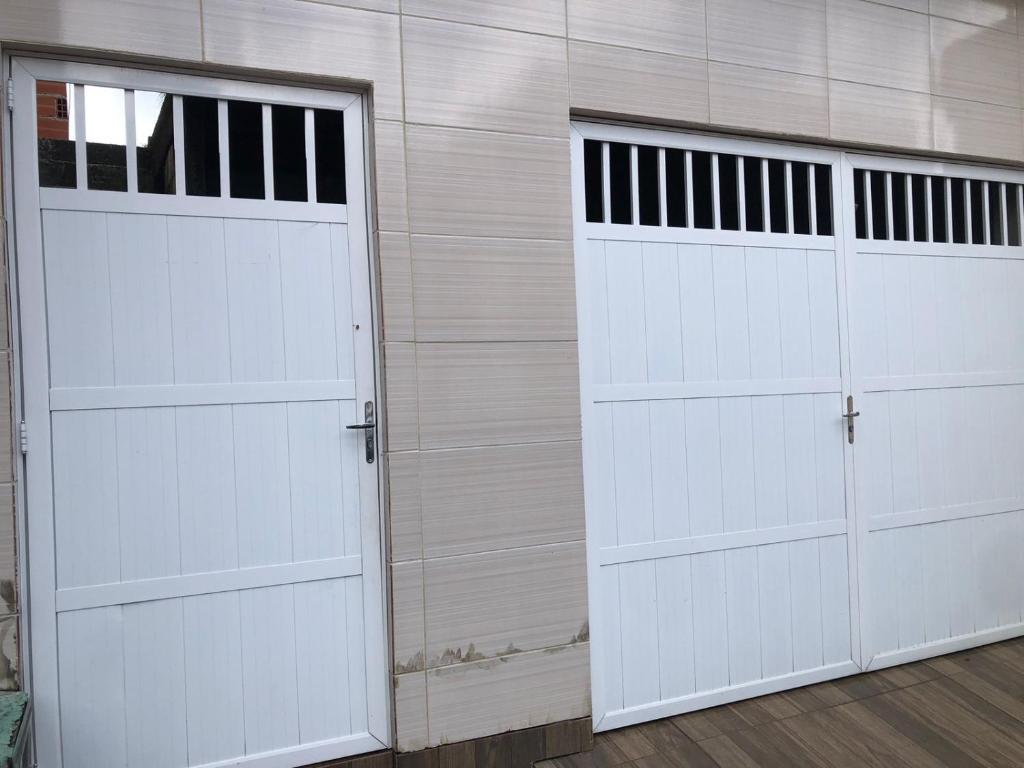 dos puertas blancas de garaje en una pared de madera en Canto da paz en Angra dos Reis