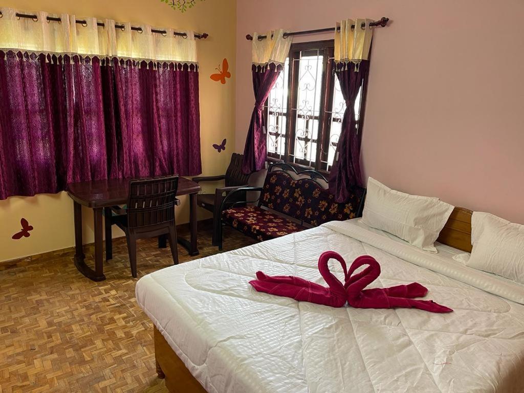 una camera da letto con un letto con un fiocco rosso sopra di Hotel PNR'S Paradise a Ooty