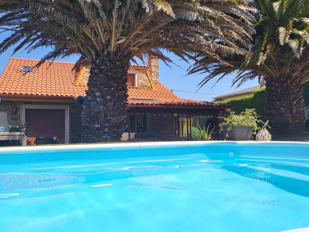 a swimming pool in front of a house with palm trees at El rincón de Mónica in A Coruña