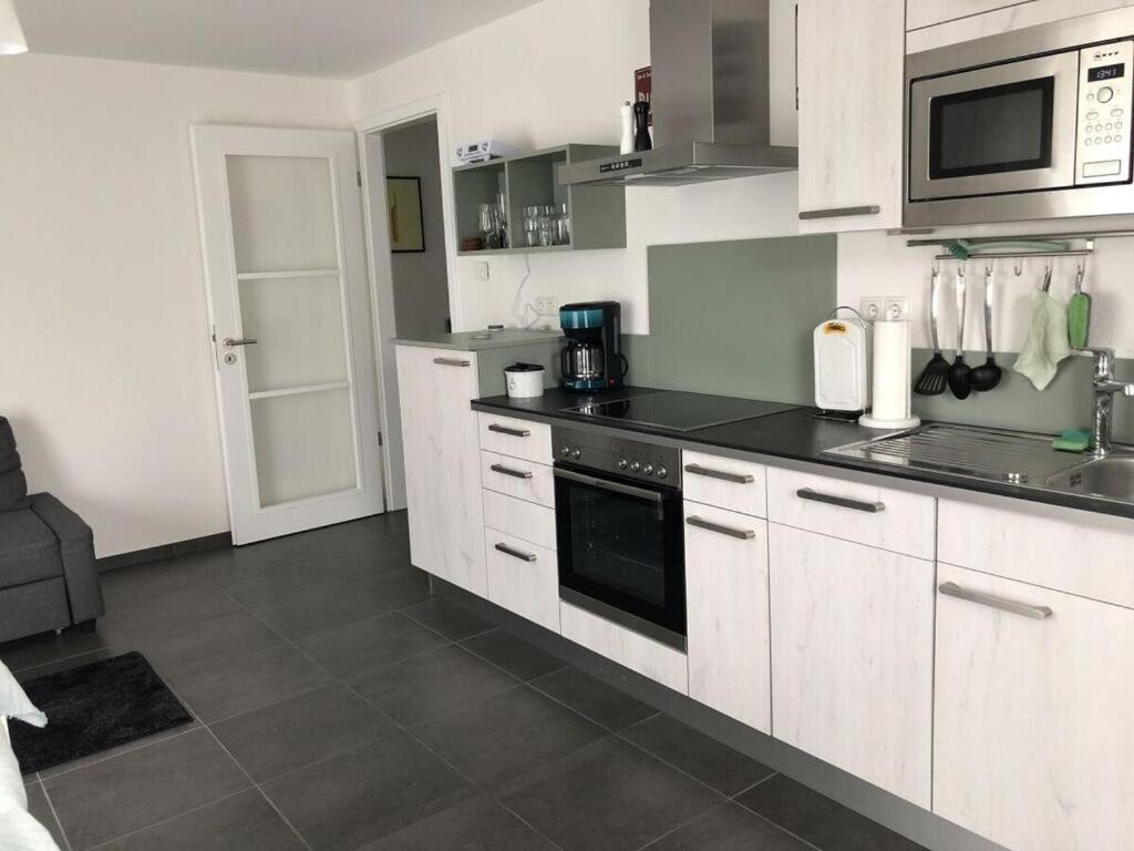 uma cozinha com armários brancos e um balcão preto em Holiday apartment meadow em Sulzburg