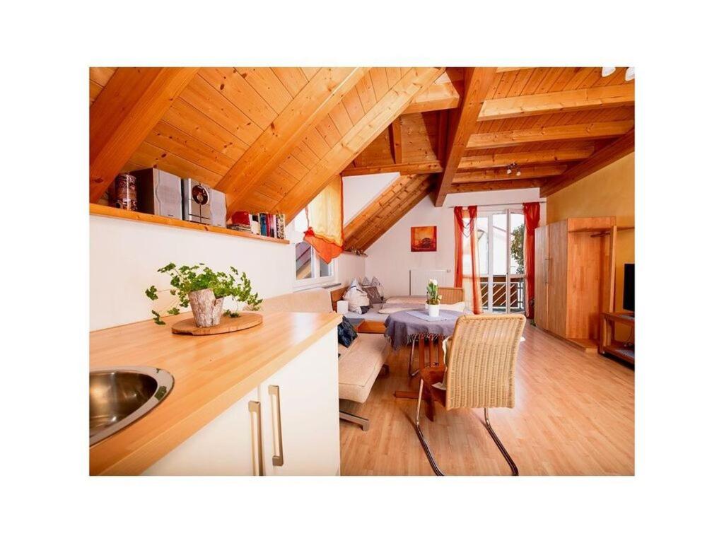 a kitchen and living room with wooden ceilings and a table at Appealing apartment with terrace in Eichstetten