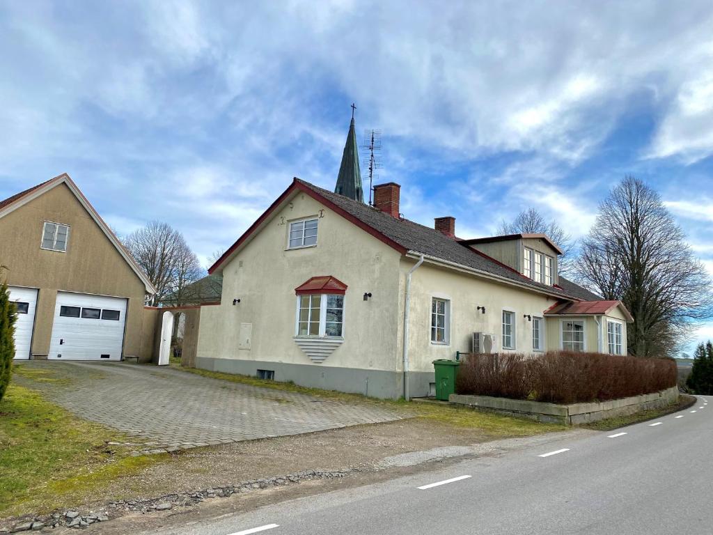 uma grande casa branca com uma torre de igreja no topo em Husrum på Österlen em Tomelilla