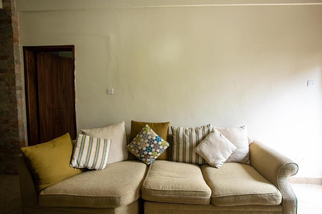 um sofá num quarto com almofadas em ST STEVENS SUITES, ENTEBBE em Entebbe