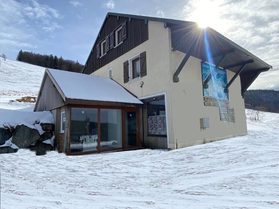 a building in the snow with the sun behind it at Chalet Rouge Gazon Altitude 1100m in Saint-Maurice-sur-Moselle