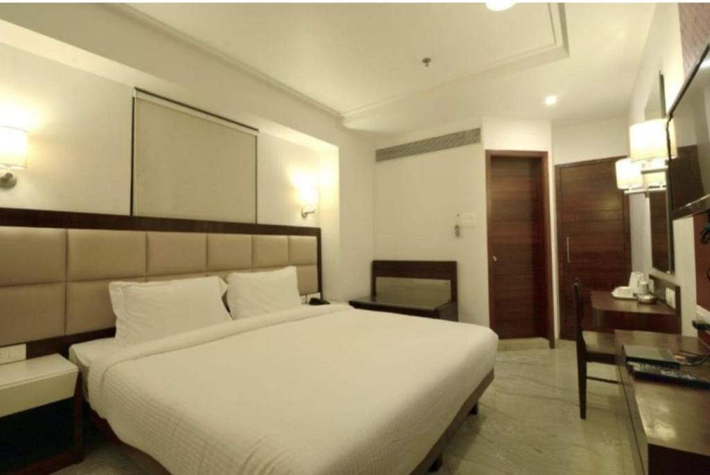 a bedroom with a large white bed and a desk at Hotel BENTLY Terminal-2 in Mumbai