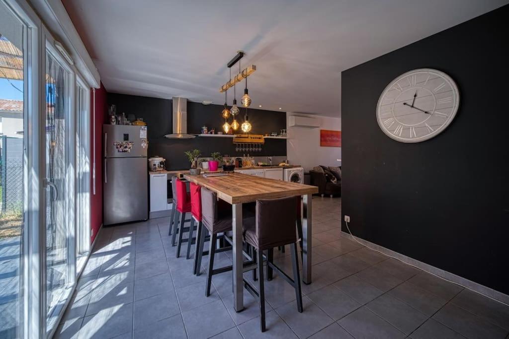 une cuisine avec une table en bois et une horloge au mur dans l'établissement Charmante maison de Lotissement, 6 couchages, à Portes-lès-Valence