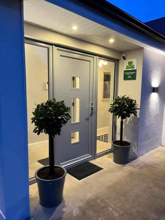 two potted trees sitting in front of a door at The Hillcrest, Luxury Accommodation in Castleblayney Town in Castleblayney