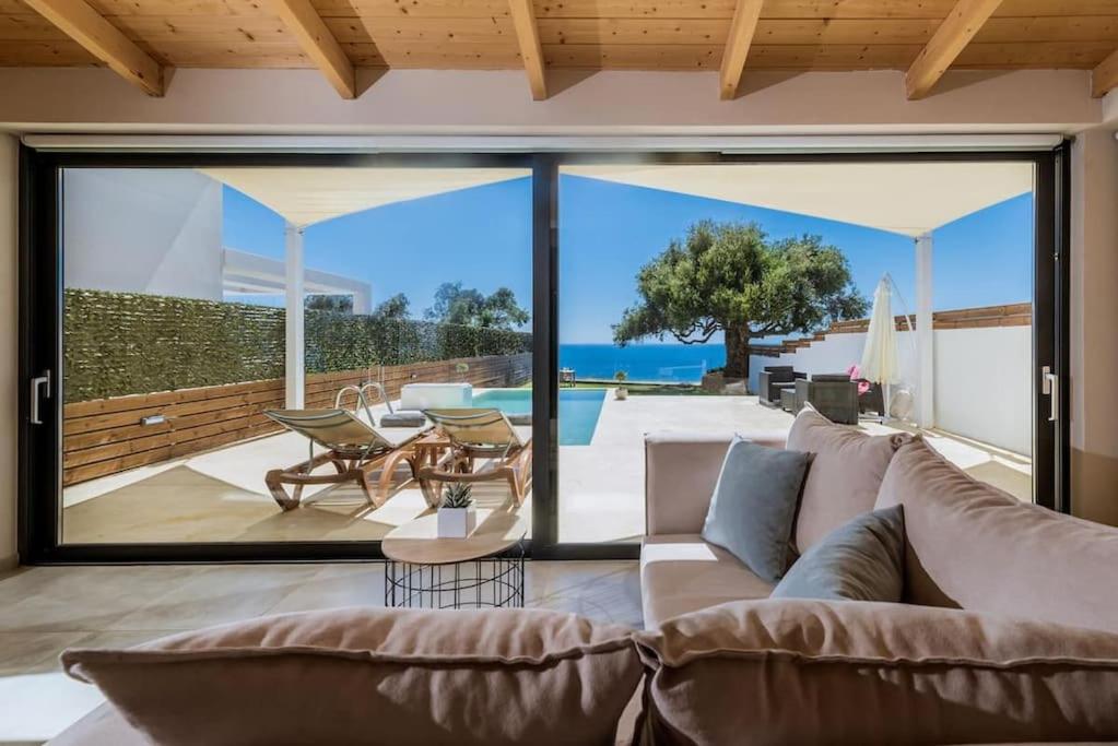 a living room with a couch and a patio at Olive Zen Villa Zante in Zakynthos Town