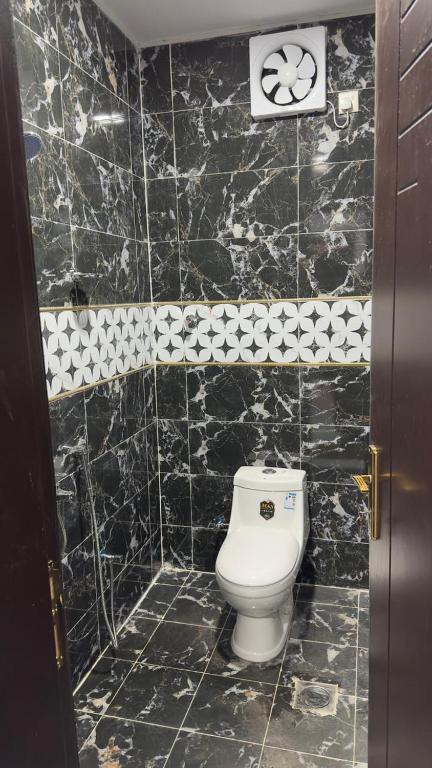 a black tiled bathroom with a white toilet in it at فندق الاقامة السعيدة in Al Bad‘