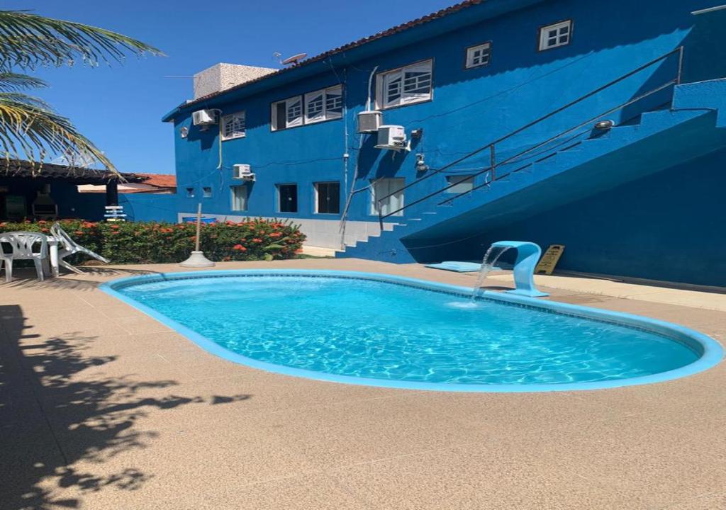a swimming pool in front of a blue building at Pousada São Miguel dos Milagres in São Miguel dos Milagres