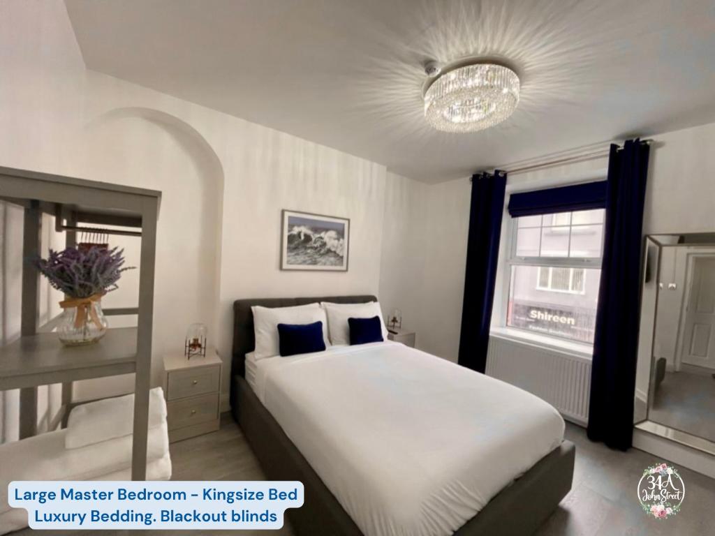 een slaapkamer met een groot wit bed en een raam bij OCEAN ESCAPE 200m From the Sea, High Spec Town Centre Entire Flat, 3 Bedrooms, TVs All Rooms in Porthcawl