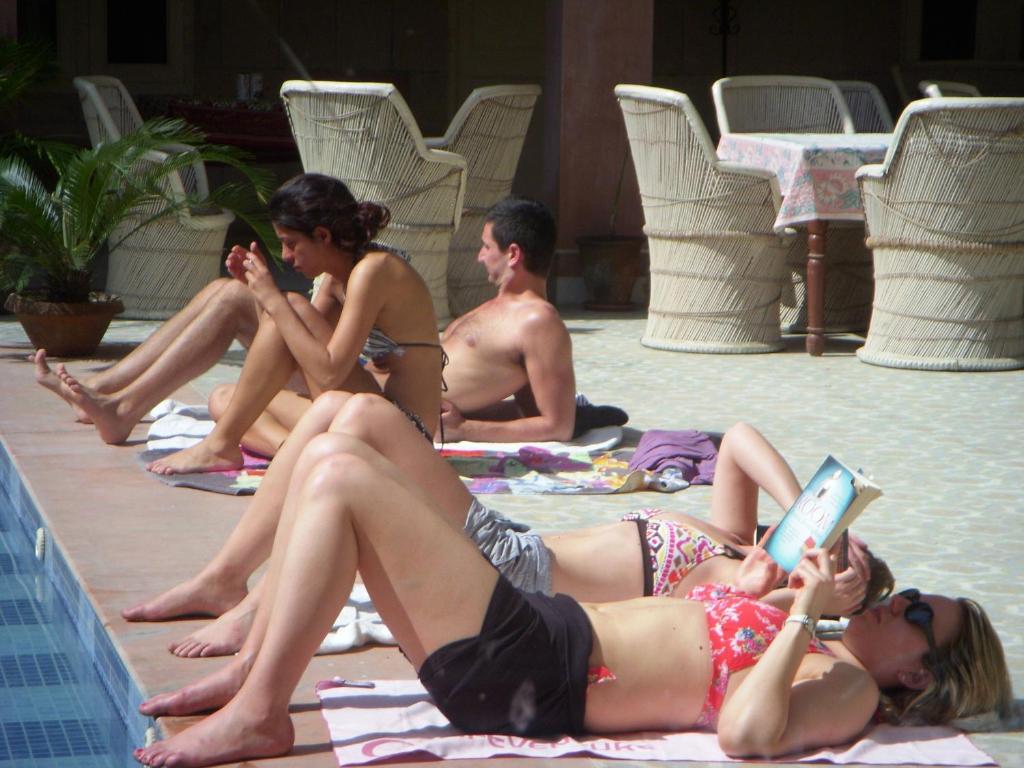 a group of people sitting around a swimming pool at Suryaa Villa - A Boutique Heritage Hotel in Jaipur