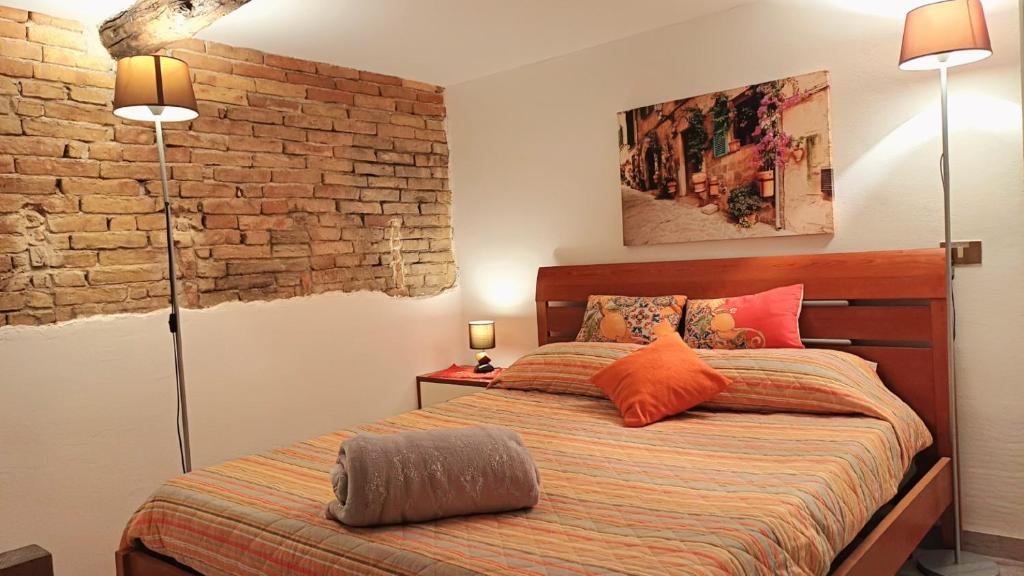 a bedroom with a bed with orange pillows and a brick wall at Casa Peppy in Palermo