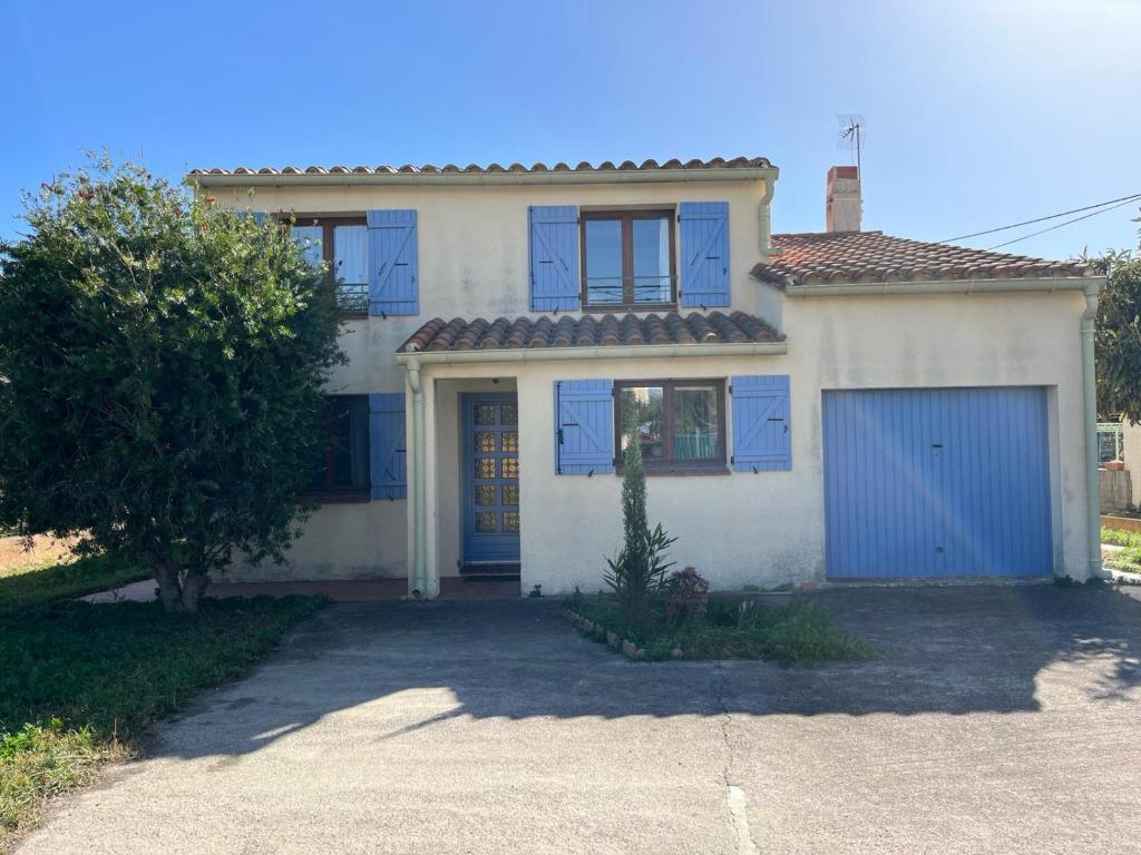 une maison blanche avec des portes bleues et un garage dans l'établissement Maison indépendante pour des vacances en famille proche de la mer et de la montagne, à Saint-Estève
