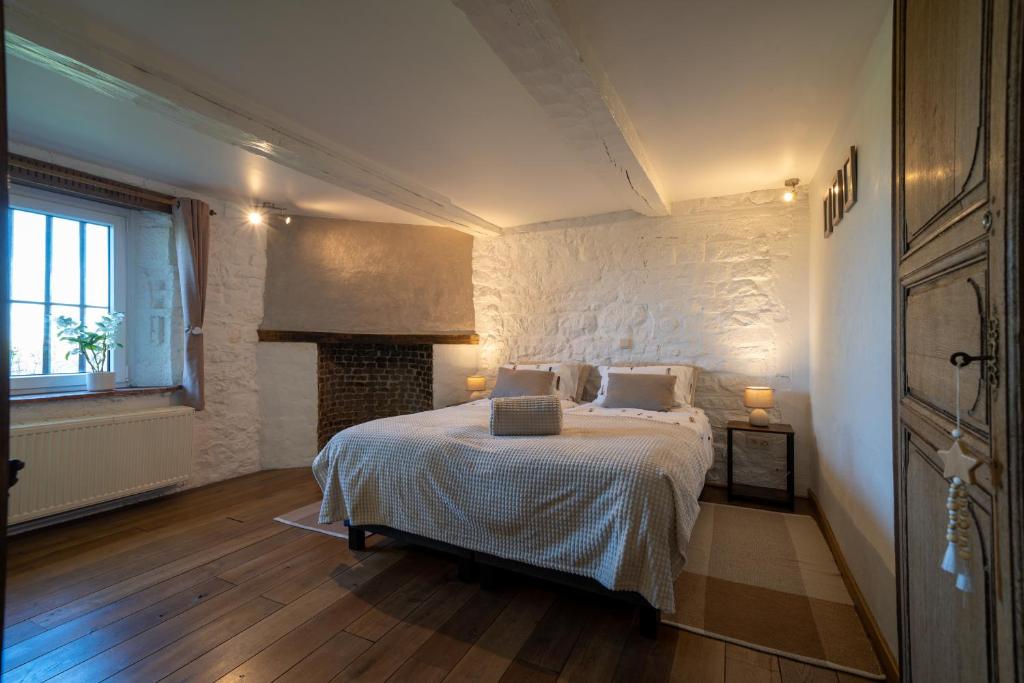 1 dormitorio con cama y pared de piedra en La ferme du Ravet - Gîte aux Lacs de l'Eau d'Heure, en Froidchapelle