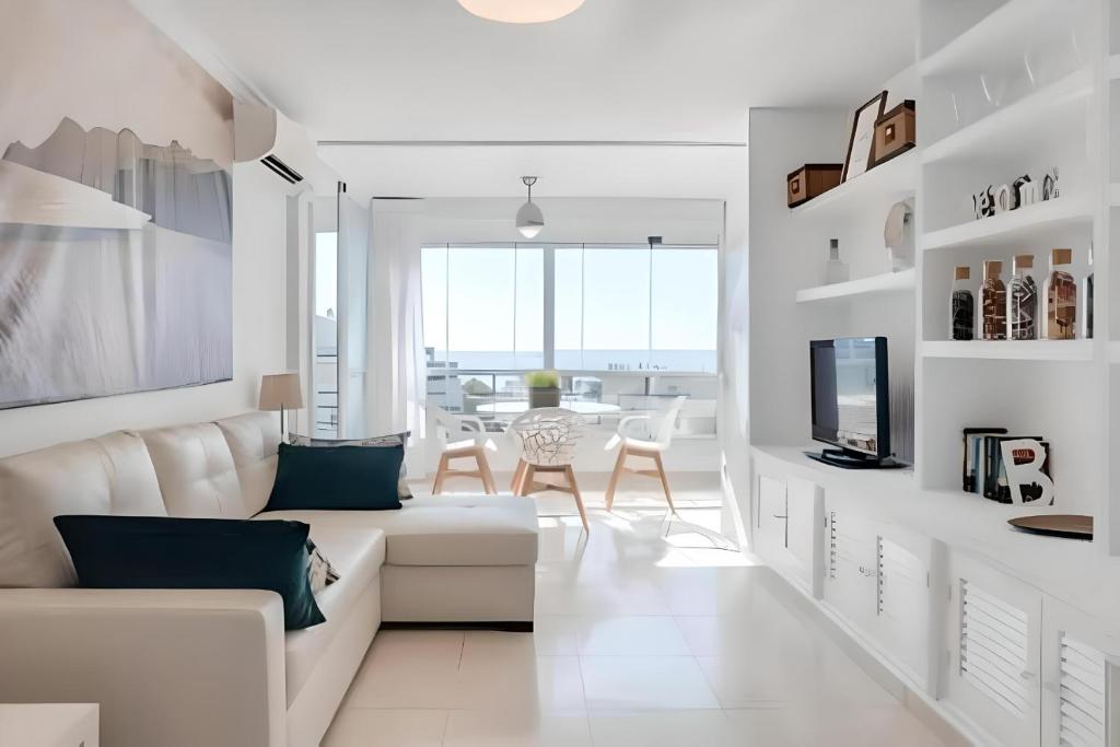 トレモリノスにあるPrecioso apartamento reformado con vistas directas al marの白いリビングルーム(白いソファ、テーブル付)