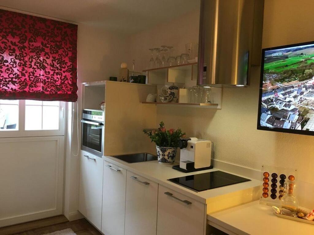 a kitchen with white cabinets and a tv on the wall at Apartment Mini Suite in Höchenschwand