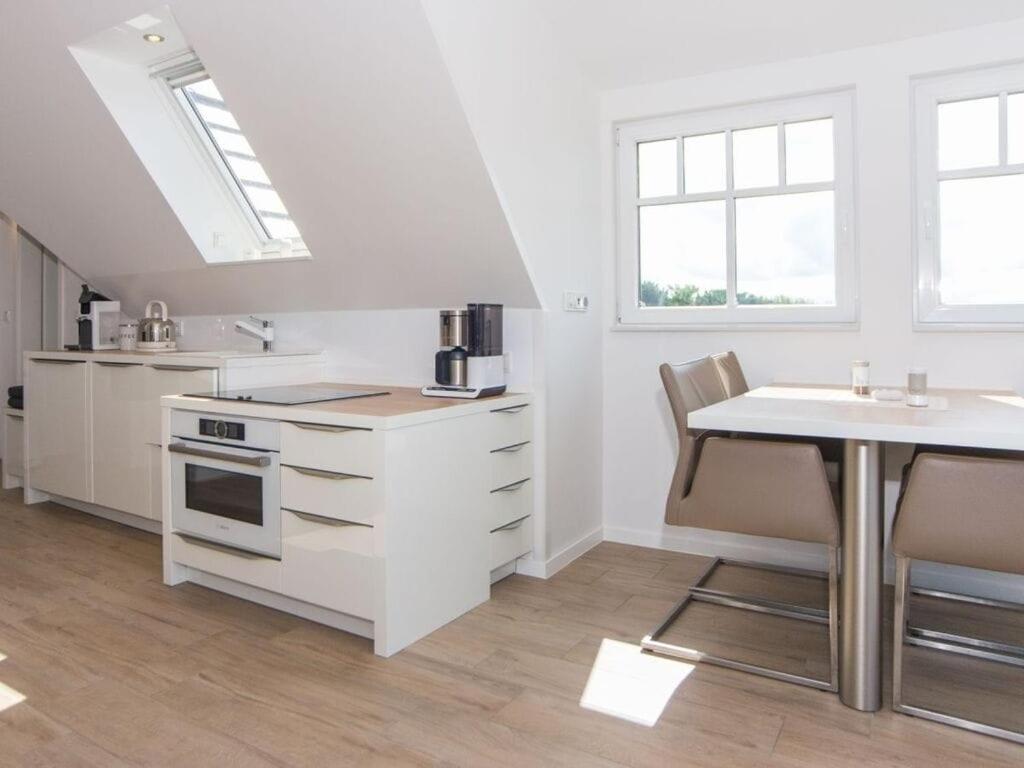uma cozinha branca com uma mesa e um lavatório em Boothäuser Living_art Wangerooge em Wangerooge