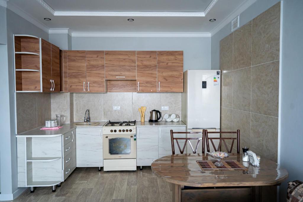 a kitchen with white cabinets and a table and a refrigerator at Квартира in Kokshetau