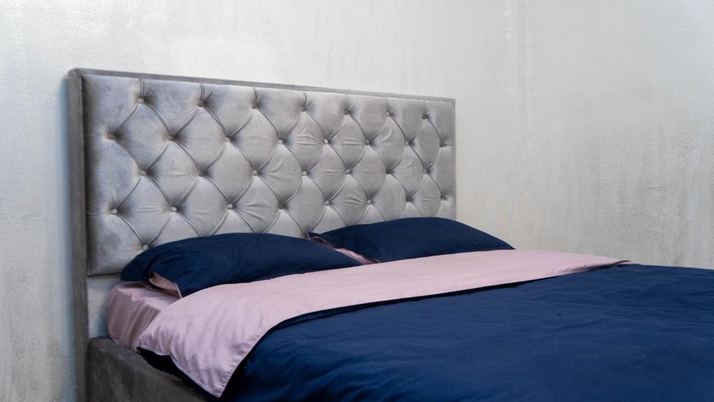 a bed with blue pillows in a bedroom at DeLuxe Ap Almaty Центр in Almaty