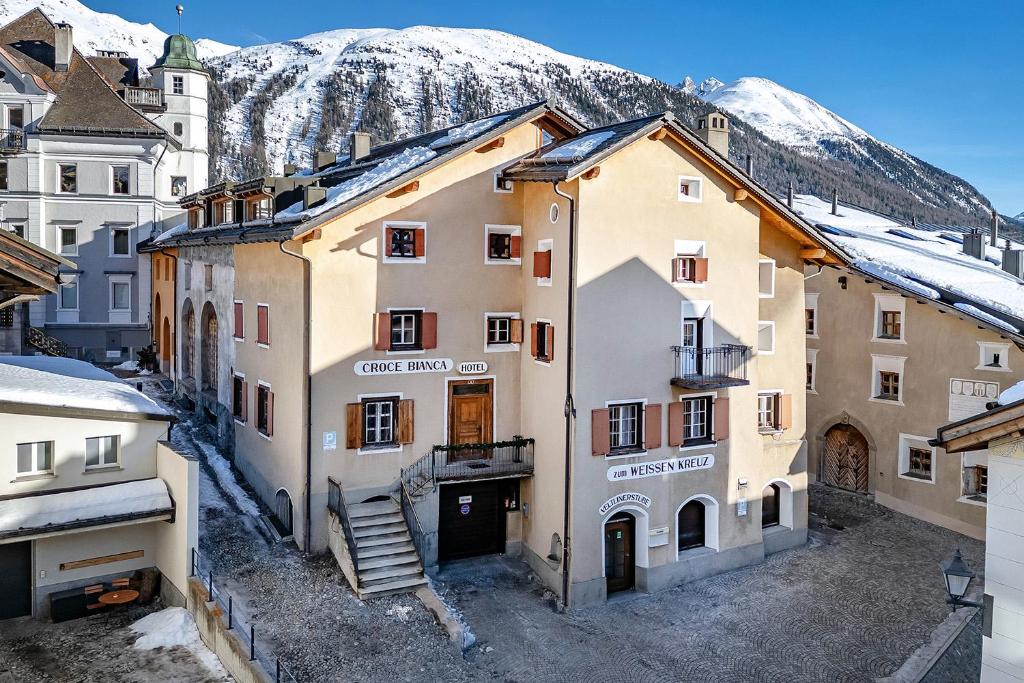 a group of buildings in a town with snow covered mountains at Weisses Kreuz - Crusch Alva in Samedan
