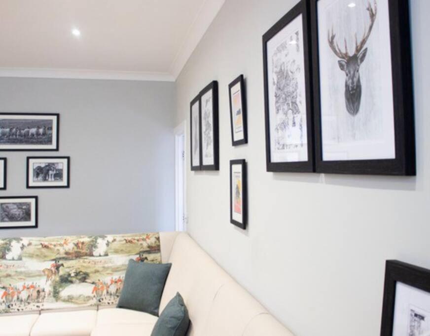 a living room with a white couch and framed pictures at Central village location in Lanchester