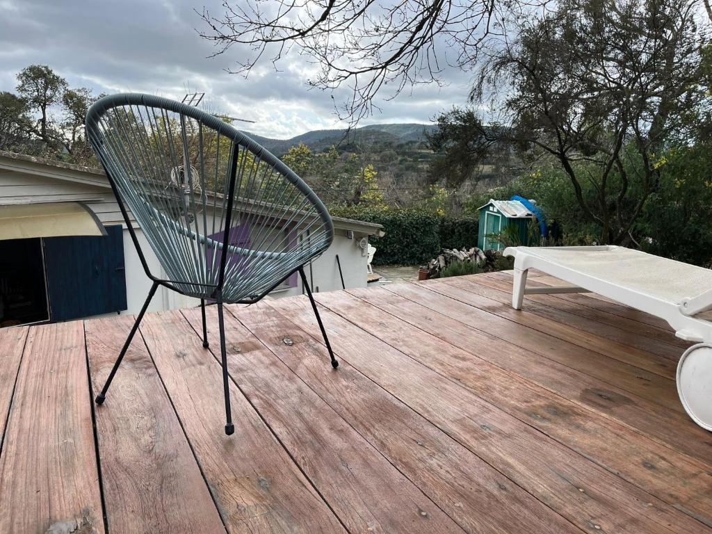 a chair sitting on a wooden deck with a bench at Chalet dans le vert in Gassin