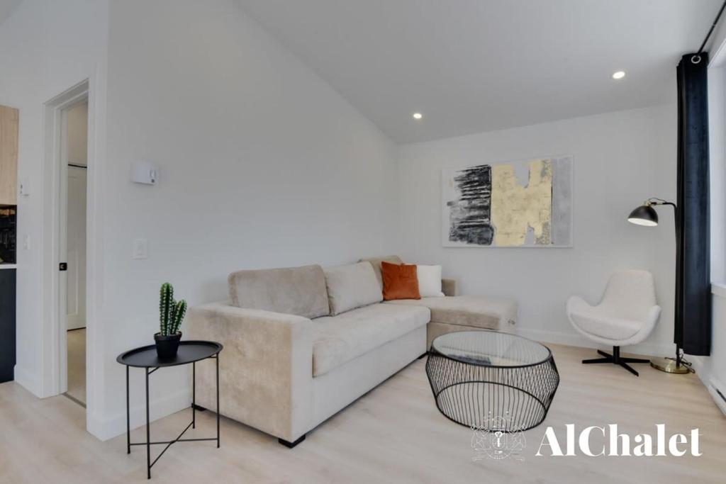 a living room with a couch and a table at Achille - Boisé avec spa et sauna in Pont-Rouge