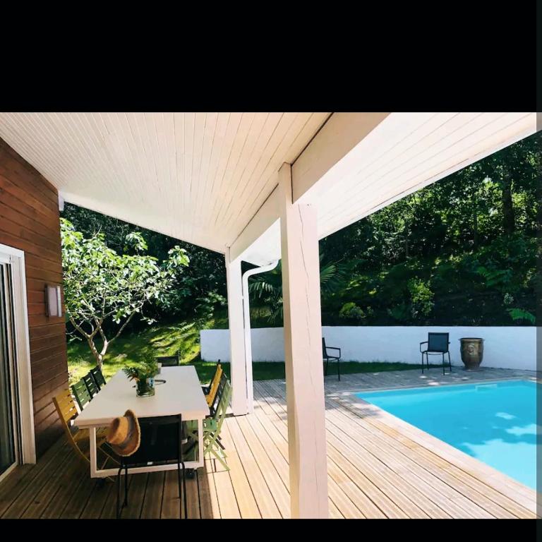 une terrasse en bois avec une table et une piscine dans l'établissement Villa Marylou, à Seignosse