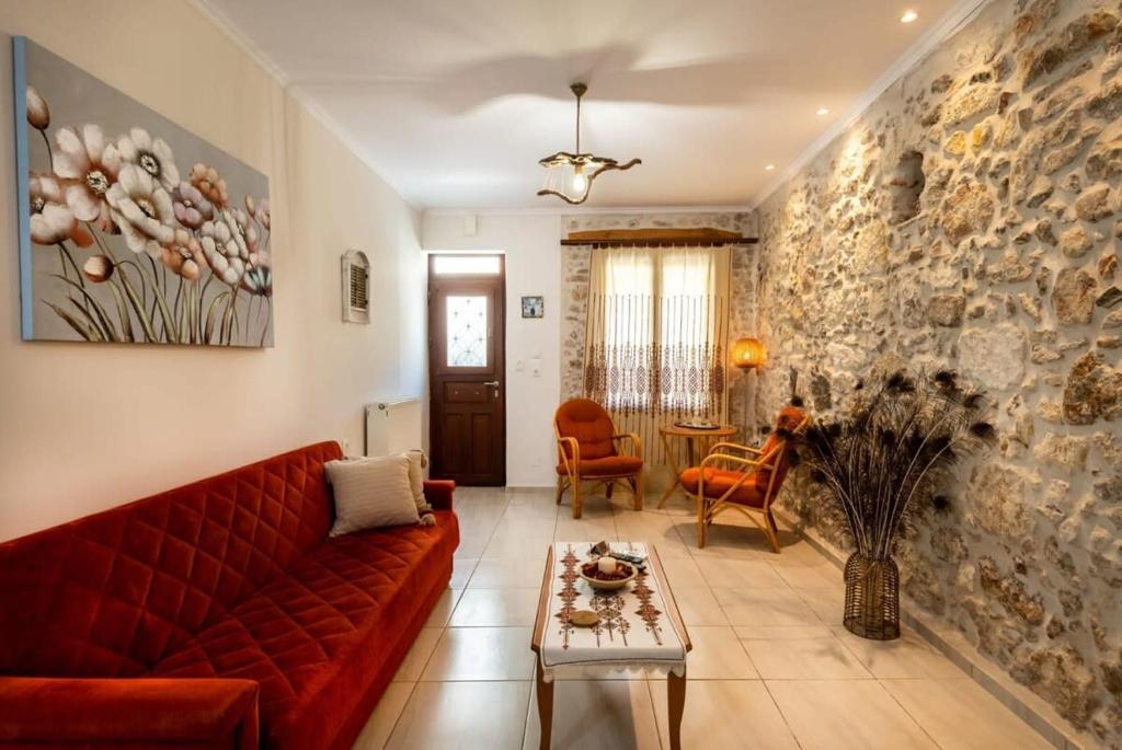 un soggiorno con divano rosso e parete in pietra di Casa Mavili, Top Location - Cozy Interiors a Rethymno