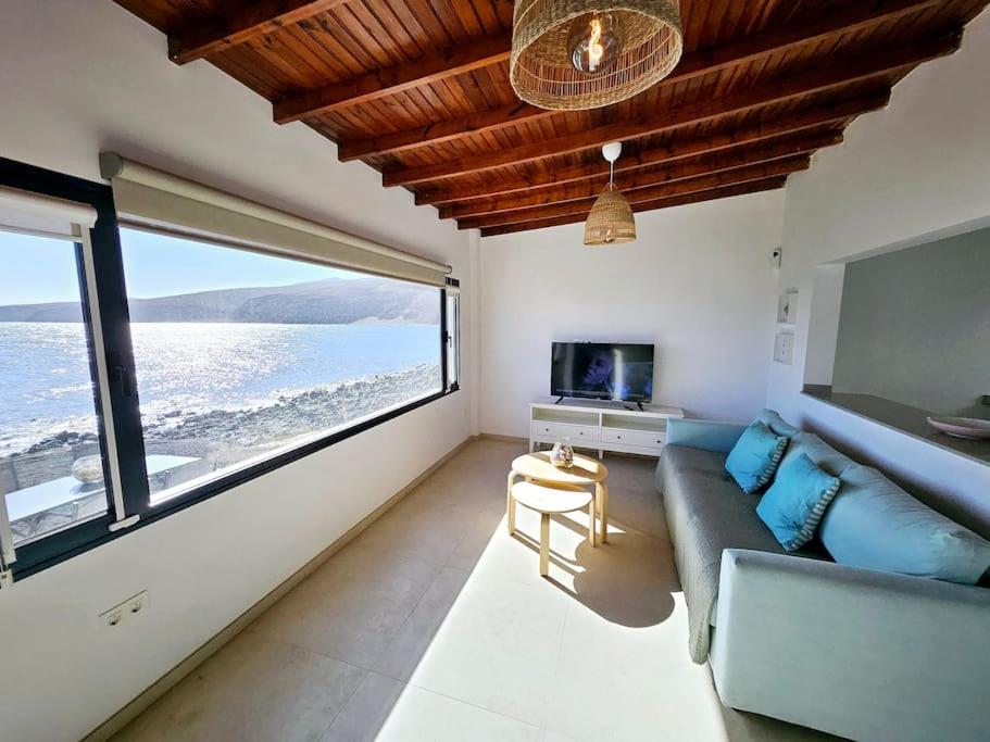 uma sala de estar com um sofá e vista para o oceano em Casa Playa Quemada junto al mar em Playa Quemada