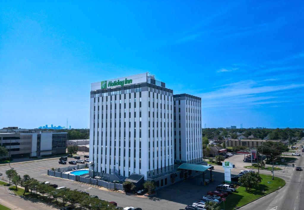 Holiday Inn Metairie New Orleans, an IHG Hotel في ميتايري: مبنى أبيض طويل مع علامة خضراء عليه