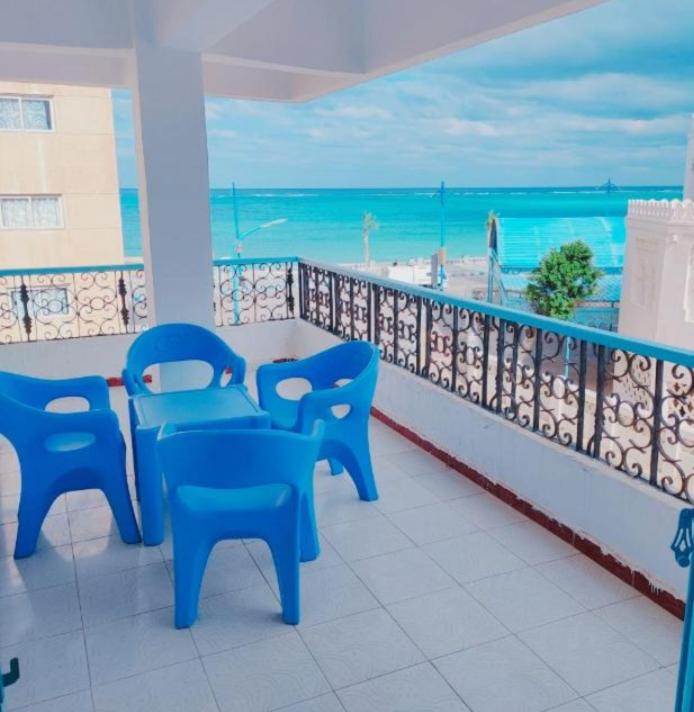 balkon z niebieskimi krzesłami i widokiem na ocean w obiekcie Queen Home Hotel w mieście Marsa Matruh